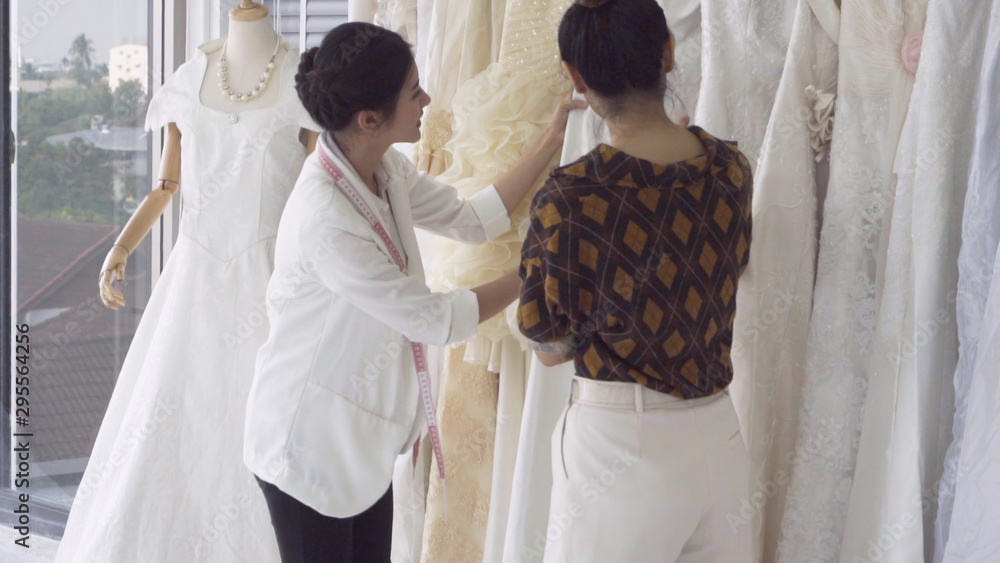 Future bride customer talking with wedding store shopkeeper to buy wedding dress and accessories for