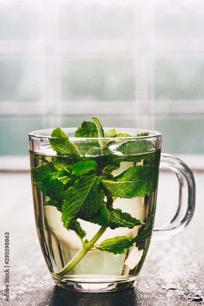 Fresh mint tea near the window. Cozy home or health concept