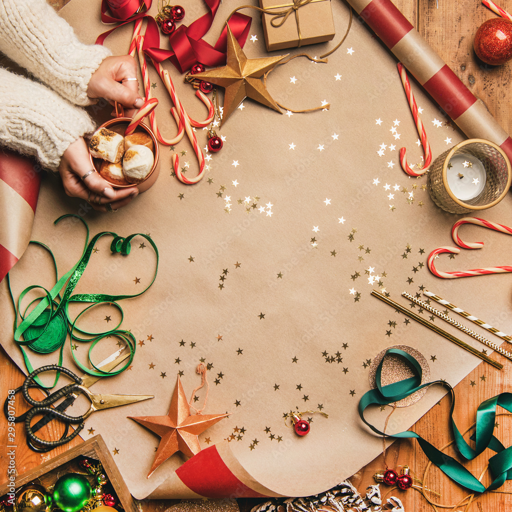 Preparing for New Year. Flat-lay of hot chocolate in mug in womans hands, candy canes, Christmas rib