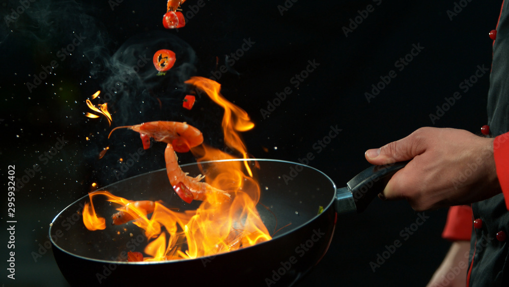 Closeup of chef holding wok pan with falling prawn