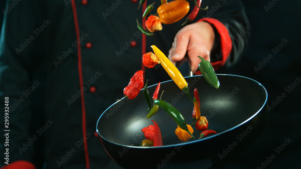 Closeup of chef holding frying with falling chilli peppers