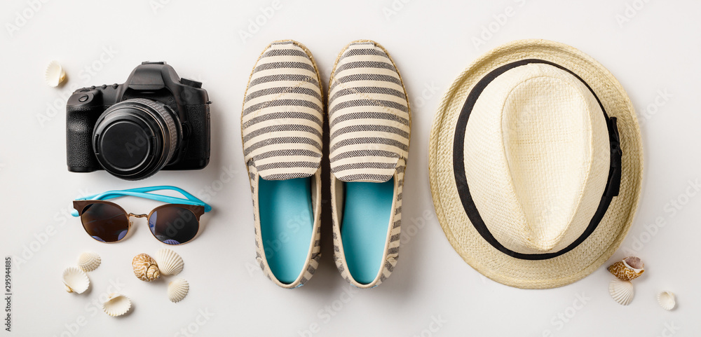 Flat lay traveler accessories on white background with palm leaf, camera and sunglasses