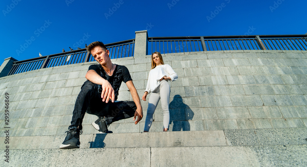 Young couple near the grey rock wall. Style photo. Flying hair. Beautiful boy and a girl. Motion pic