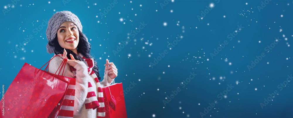 Young woman holding shopping bags in a snowy night