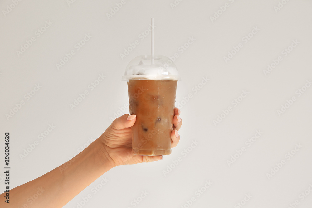 女性手拿一杯清淡背景的美味frappe咖啡