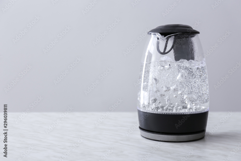 Transparent electric kettle with boiling water on table