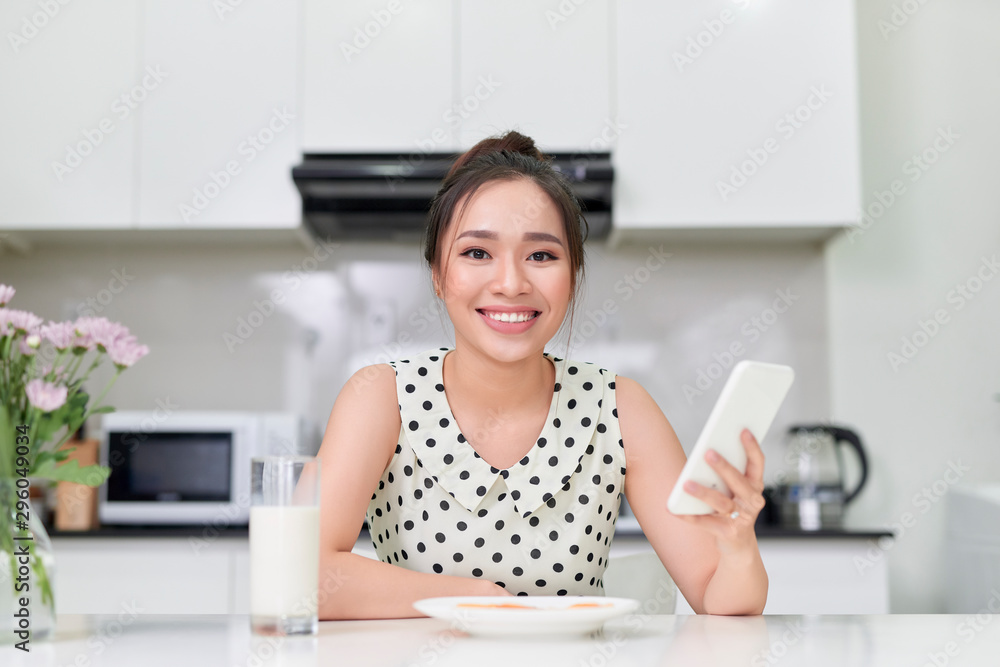 厨房里的年轻女孩拿着电话，早餐里有牛奶和饼干