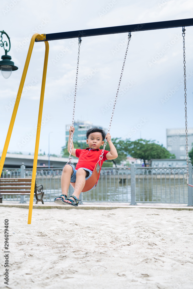 Adorable little boy having fun on a swing outdoor