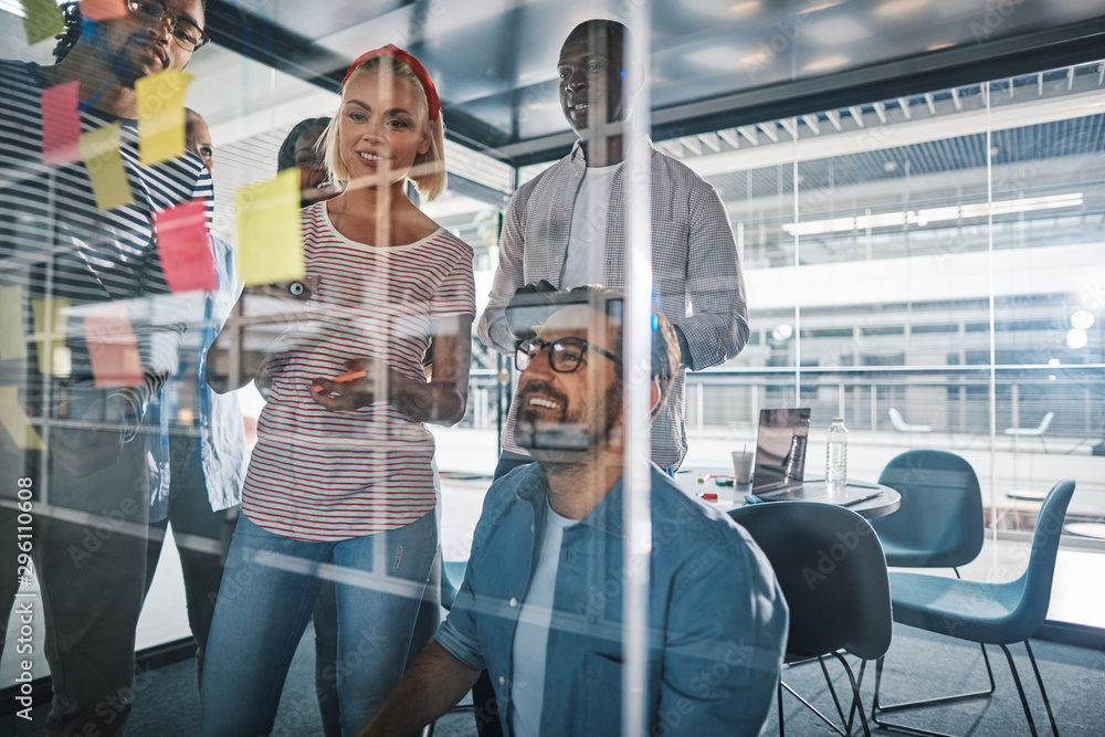 Smiling businesspeople brainstorming on the glass wall of a boar