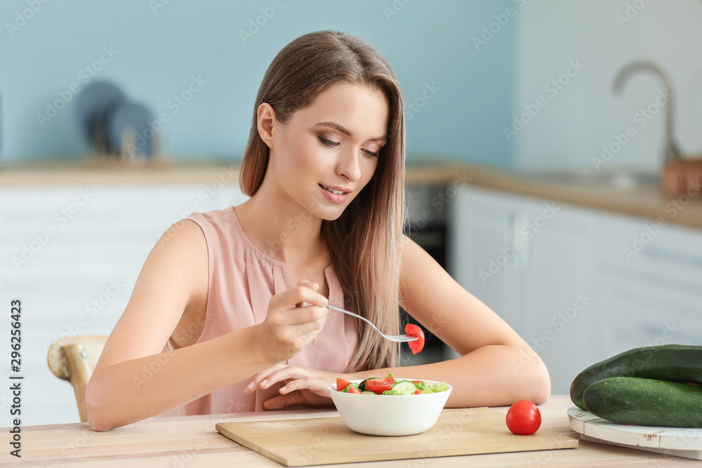 年轻女性在厨房吃健康蔬菜沙拉。饮食理念