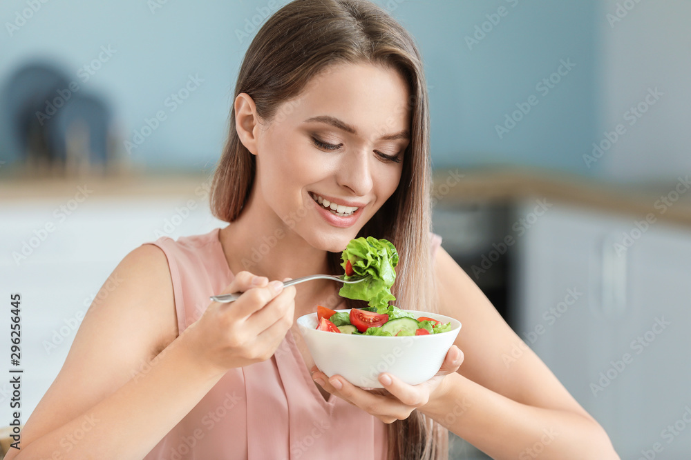 年轻女性在厨房吃健康蔬菜沙拉。饮食理念