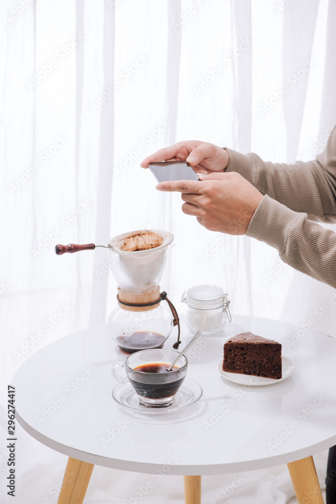 英俊的亚洲人在咖啡馆拍巧克力蛋糕和牛奶的照片。甜点或食物摄影h