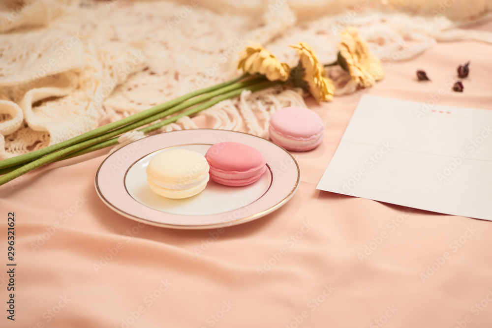 Envelope, flowers, and macarons with cup of tea on light background