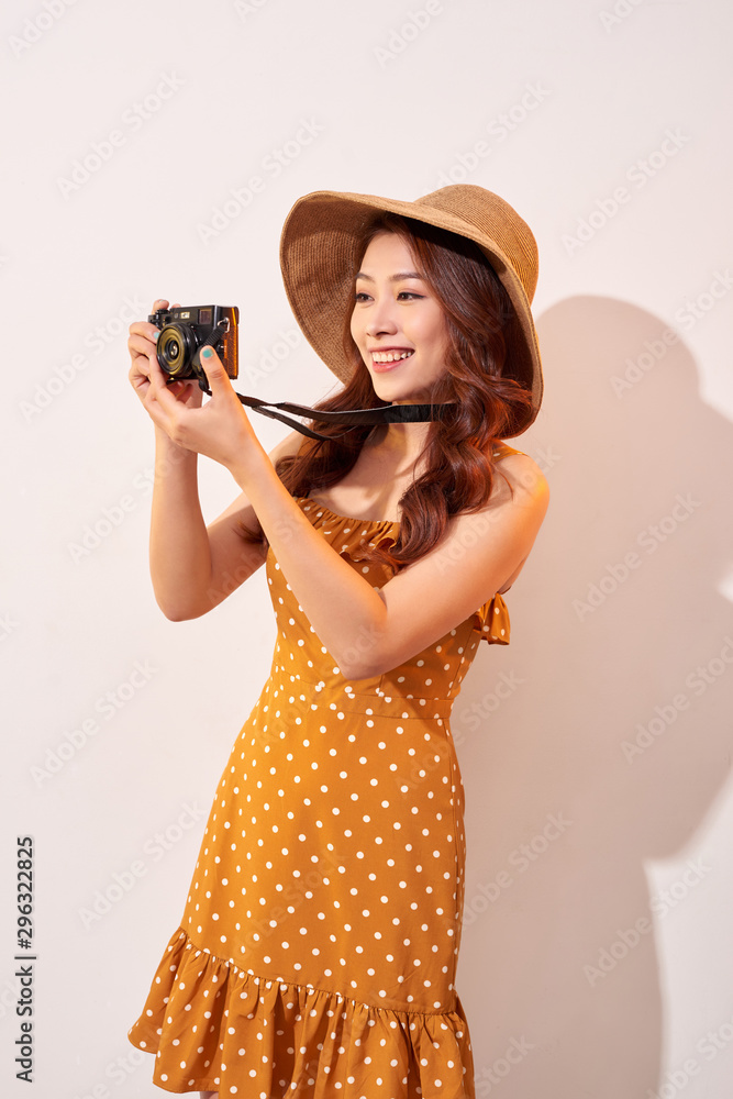 Image of young photographer woman isolated over beige background wall holding camera.