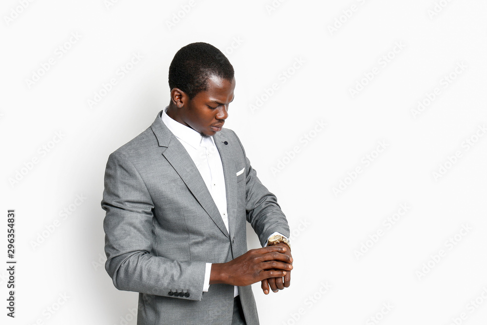 Handsome African-American businessman looking at watch against white background