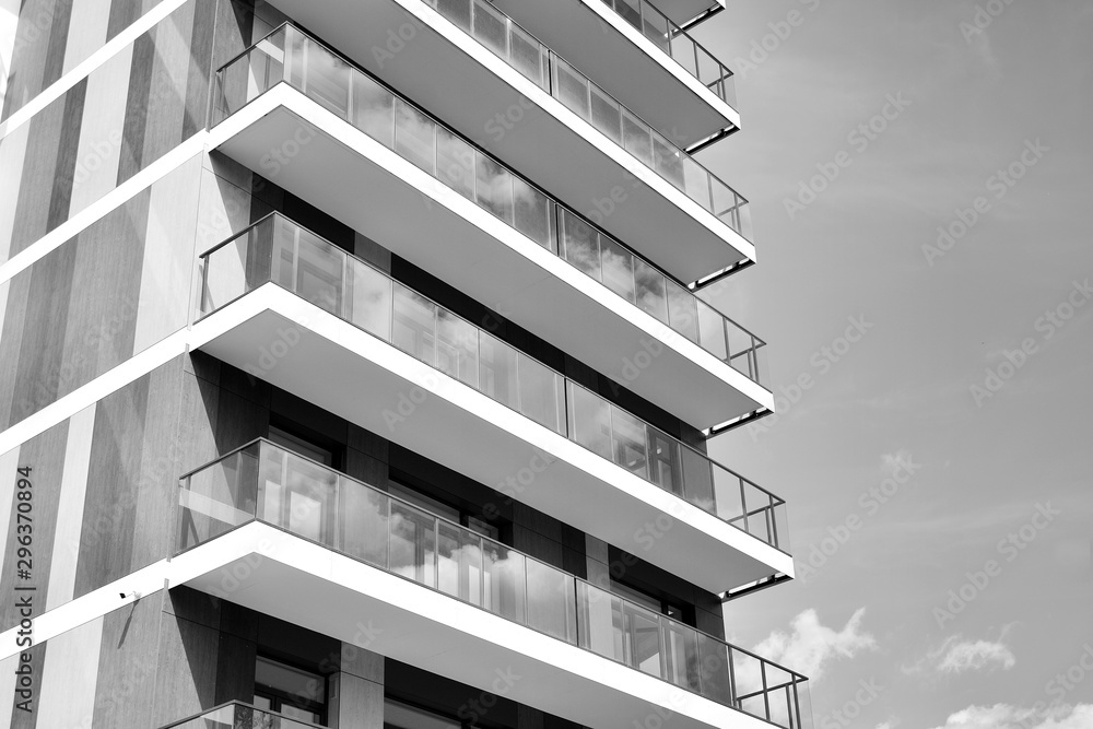 Fragment of a facade of a building with windows and balconies. Modern home with many flats. Black an