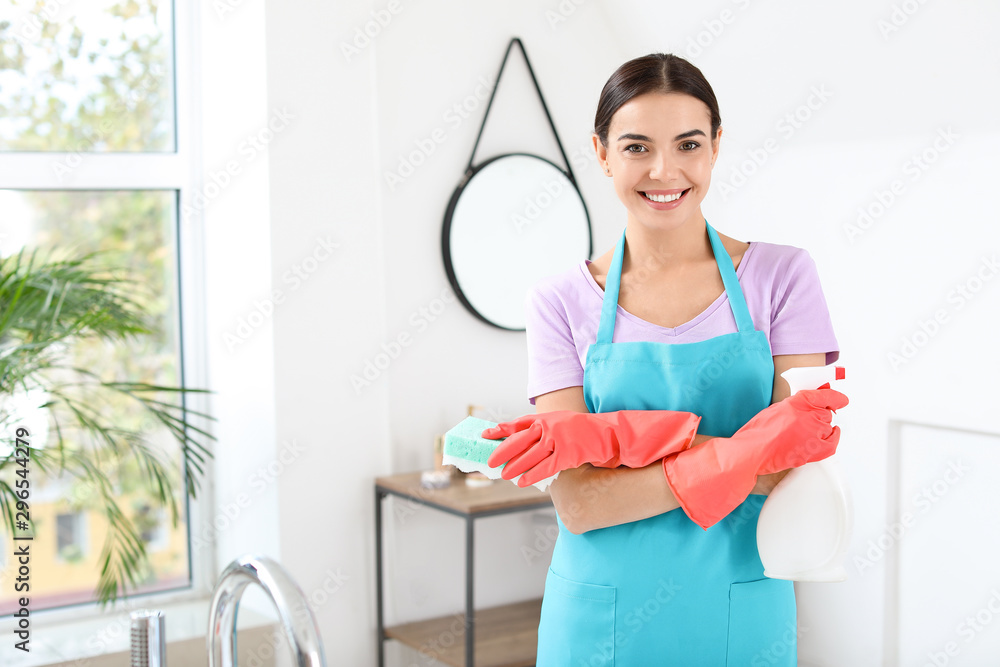 Beautiful young woman with cleaning supplies in bathroom