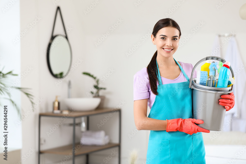 Beautiful young woman with cleaning supplies in bathroom