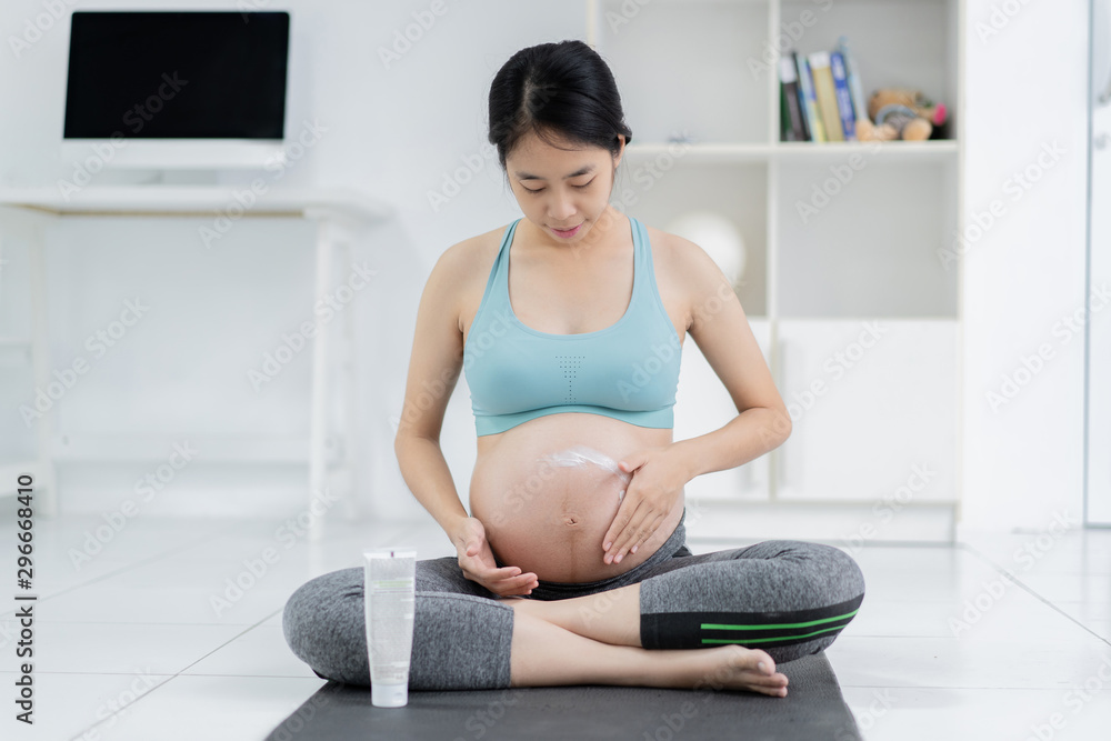 孕妇，她正在胃里涂面霜，防止皮肤破裂。