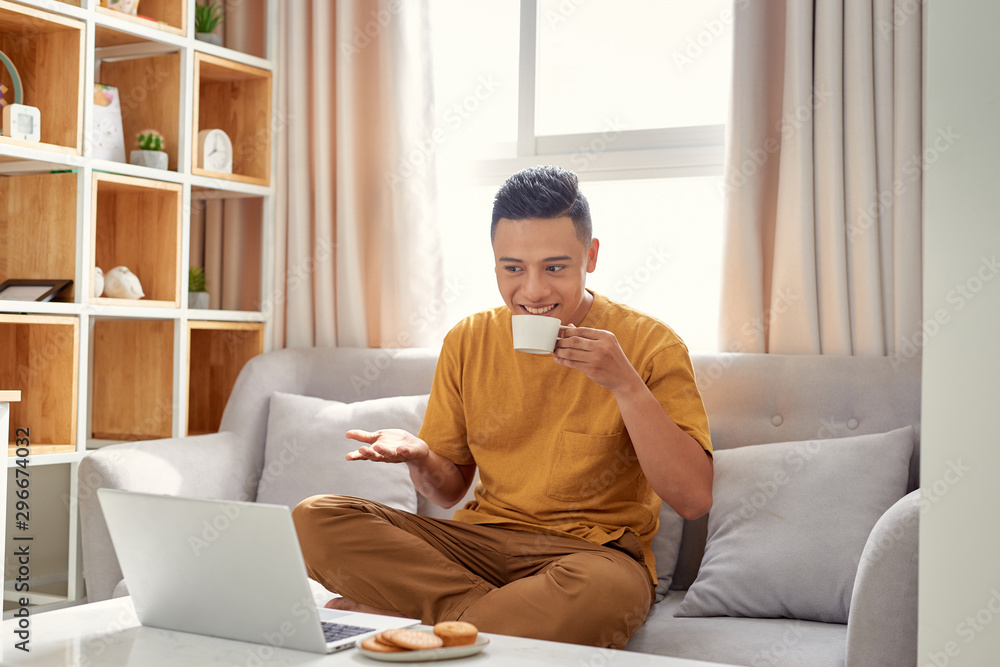 happy young Man sitting in sofa and using laptop