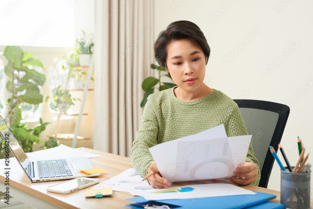 Concentrated woman sit at table reading documents and taking note