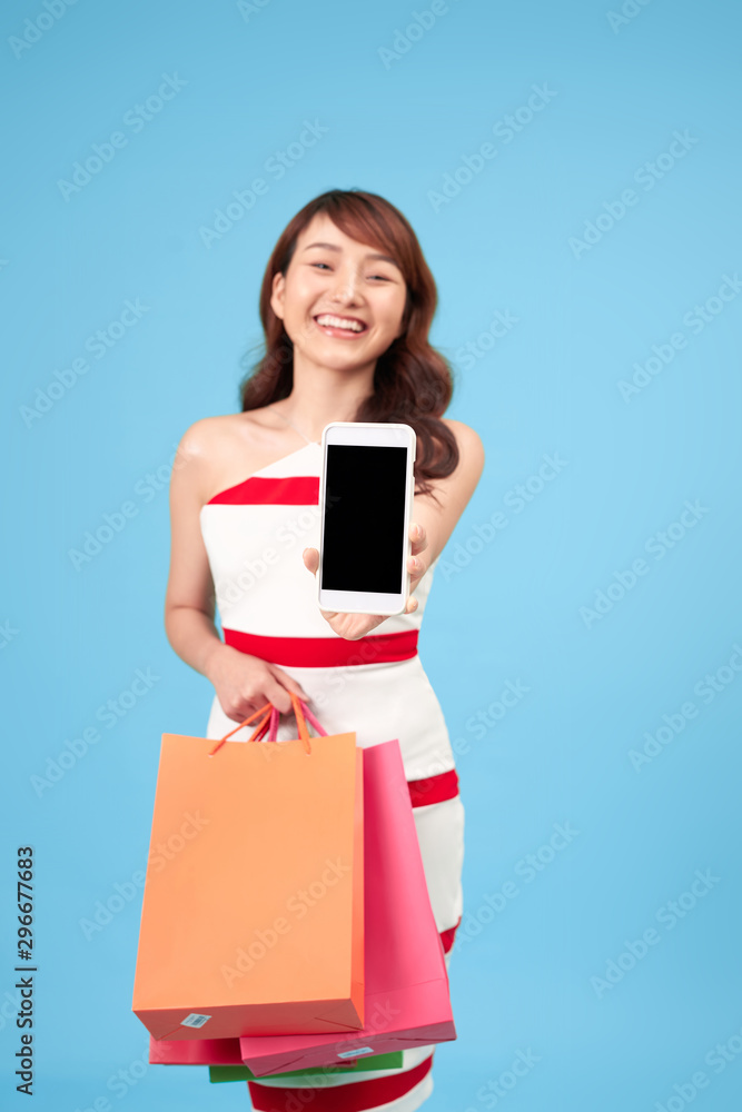 Stylish young woman with shopping bags and smart phone in hands