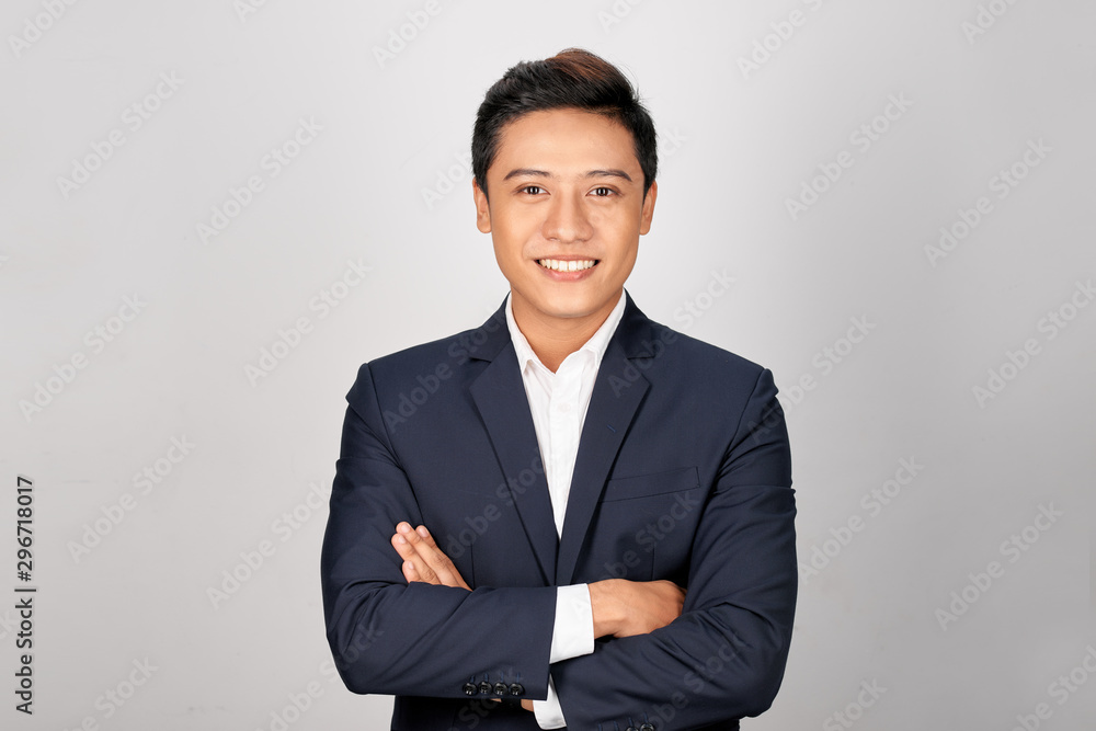 Happy Asian young businessman standing cross-armed on white background