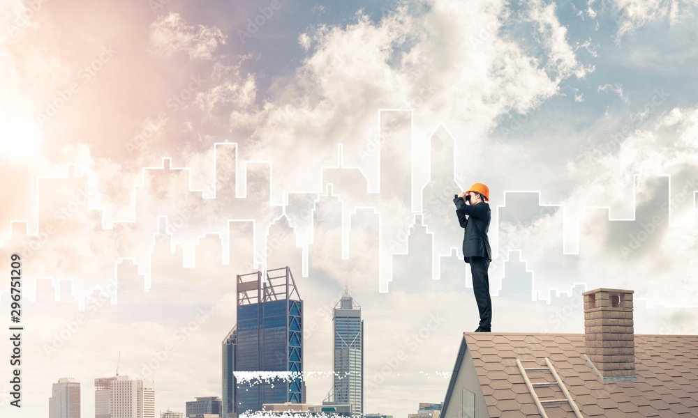 Engineer man standing on roof and looking in binoculars. Mixed m