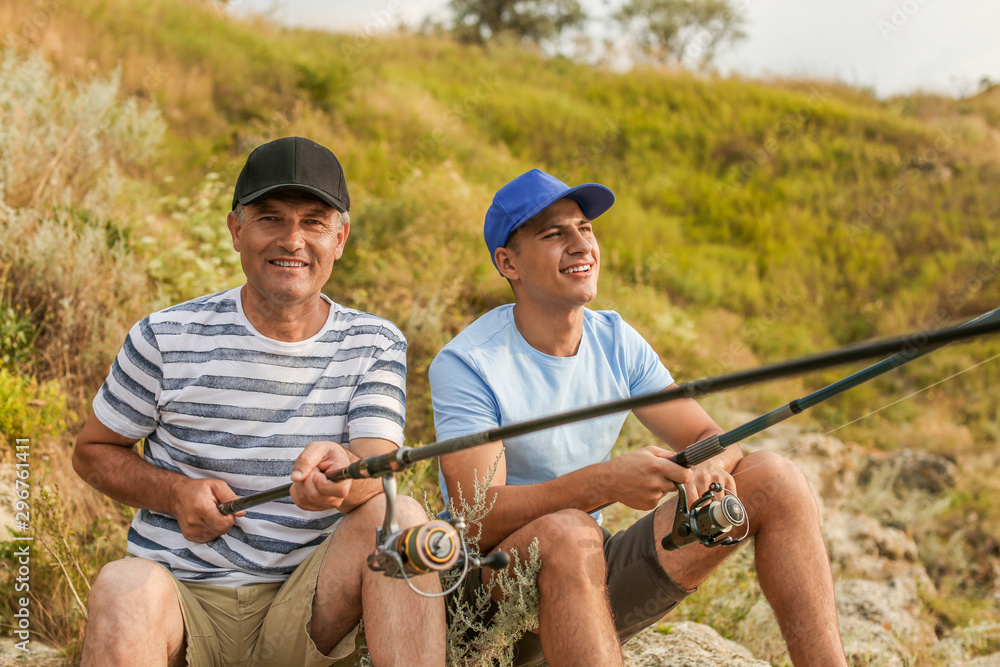 Young man and his father fishing on river