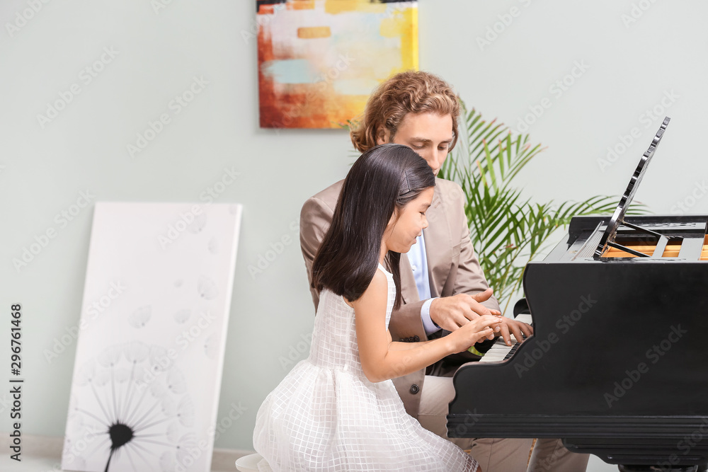 Man teaching little girl to play piano