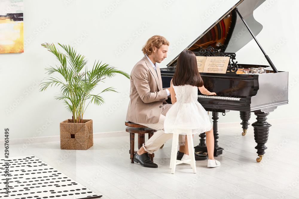 Man teaching little girl to play piano