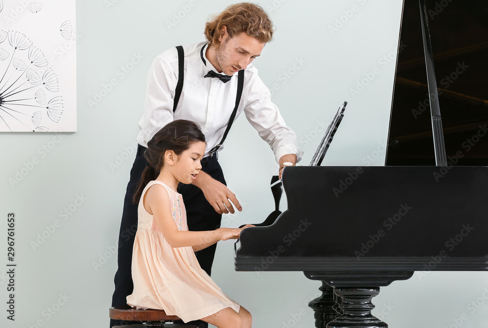 Man teaching little girl to play piano