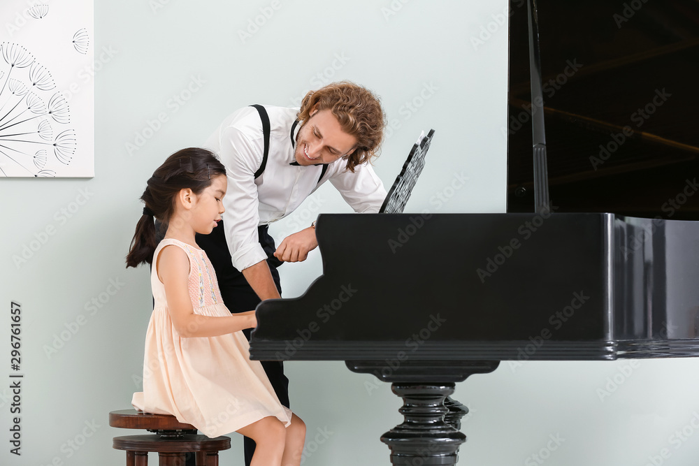 Man teaching little girl to play piano