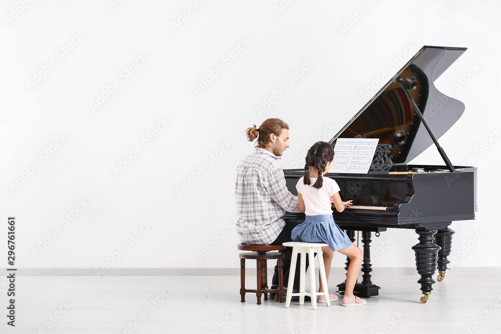 Man teaching little girl to play piano