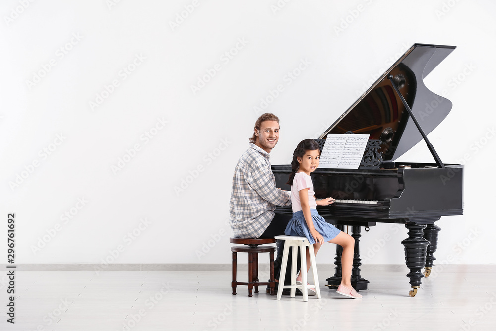 Man teaching little girl to play piano