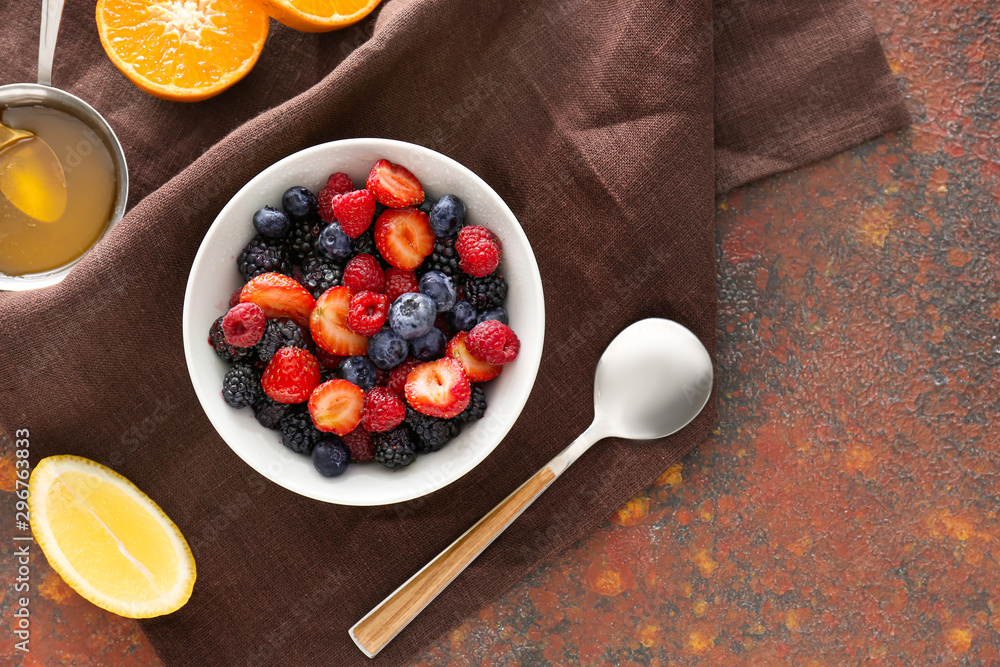 Bowl with tasty fruit salad on color background