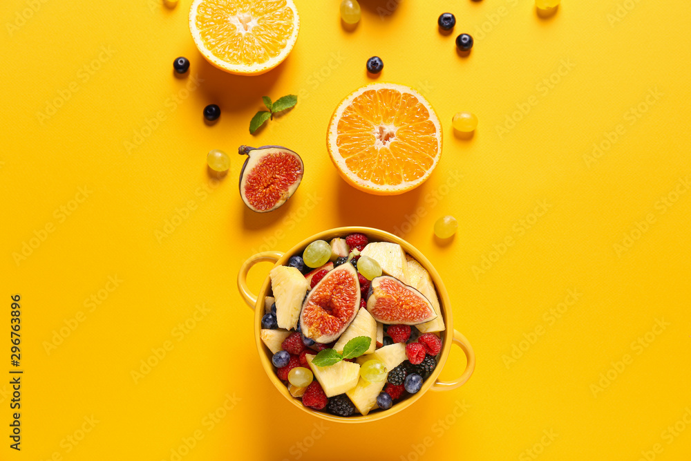 Pot with tasty fruit salad on color background