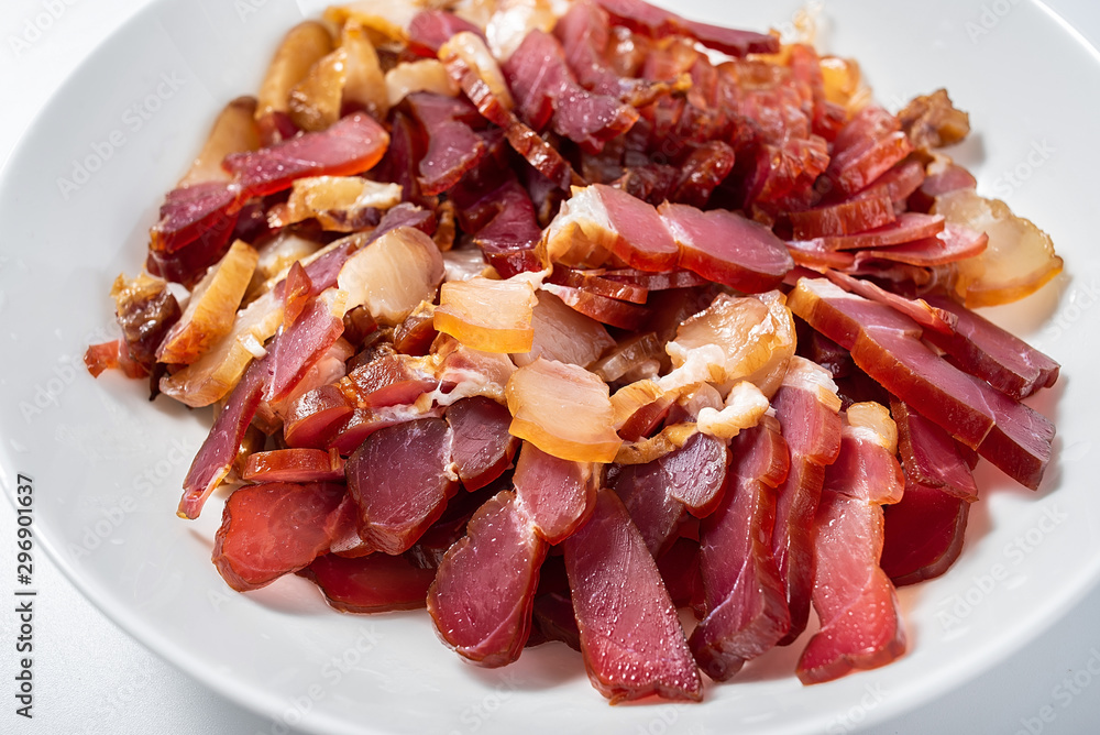 A plate of red Hunan Xiangxi smoked bacon slices on a white background