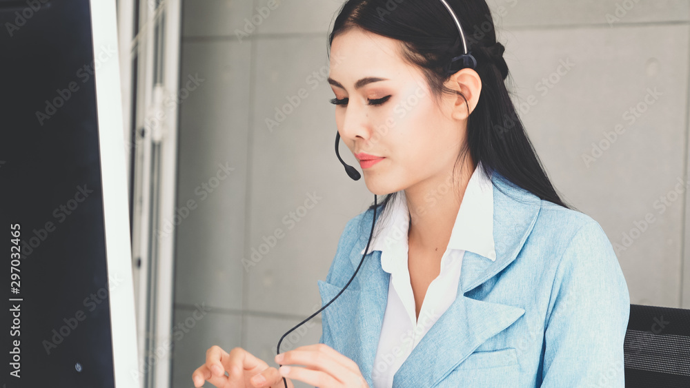 Customer support agent or call center with headset works on desktop computer while supporting the cu