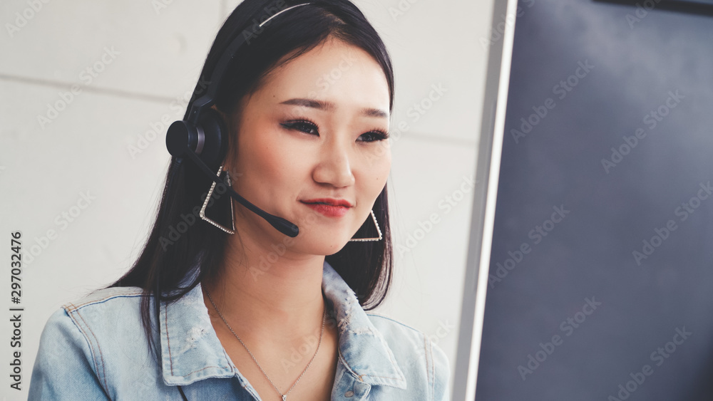 Customer support agent or call center with headset works on desktop computer while supporting the cu