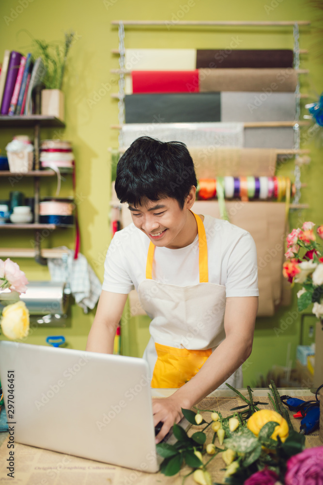 年轻的花店老板在店里用笔记本电脑工作