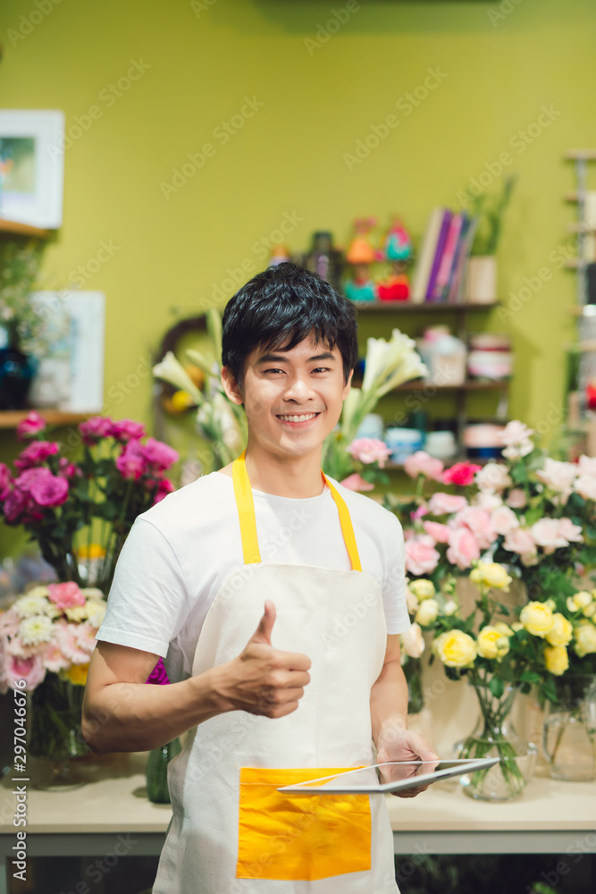 微笑的男性花店老板在花店拿着剪贴板的肖像