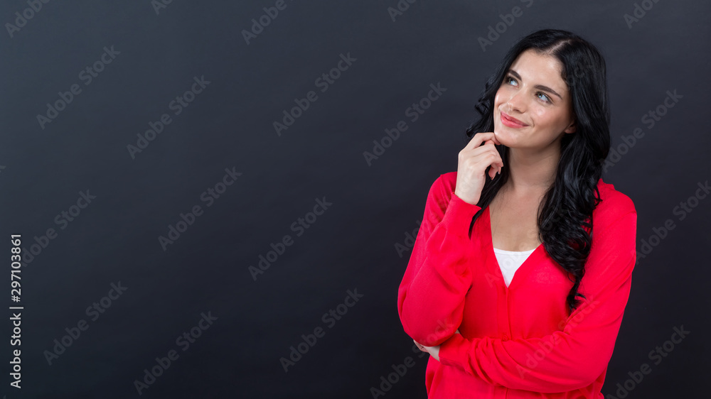 Young woman in a thoughtful pose on a black background