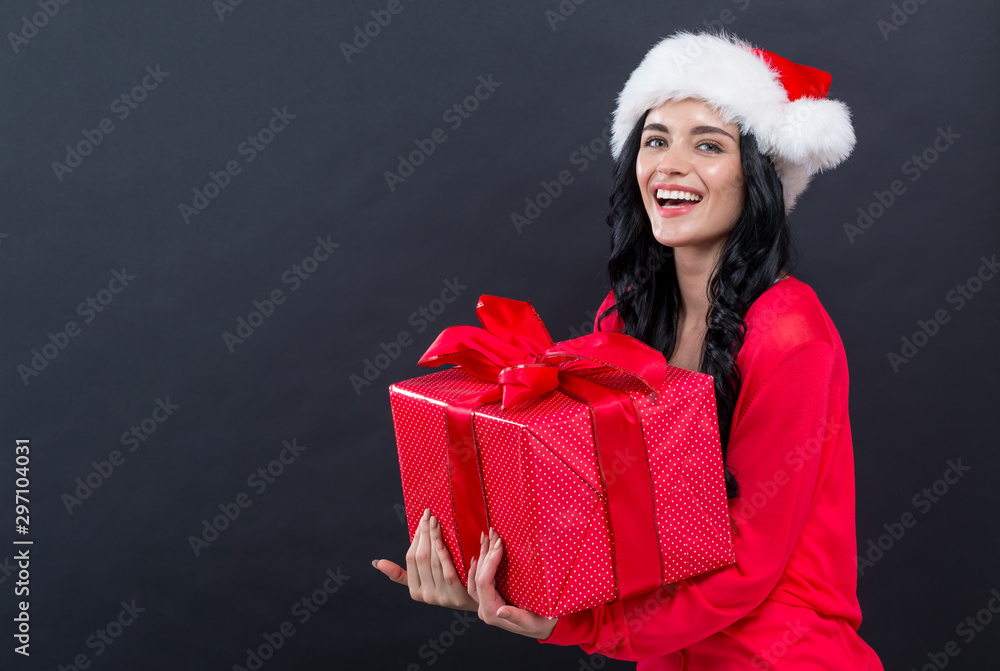 Young woman with santa hat holding a gift box on a black background