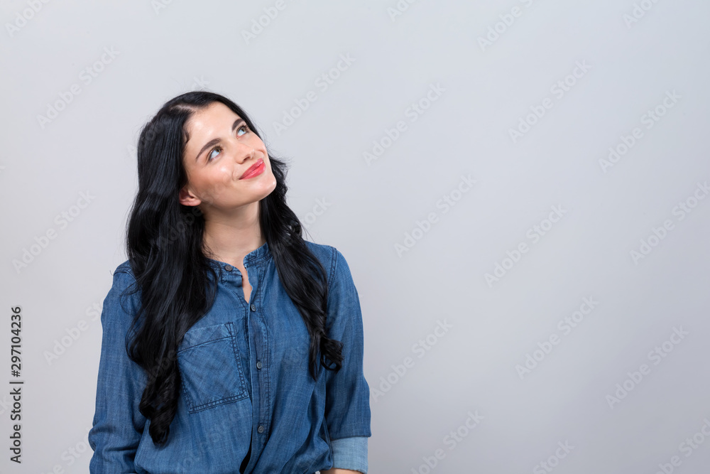 Young woman in a thoughtful pose on a gray background