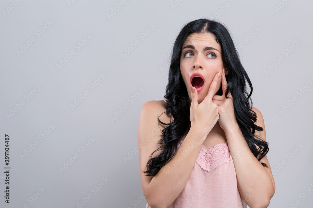 Young woman with skin blemish theme on a gray background