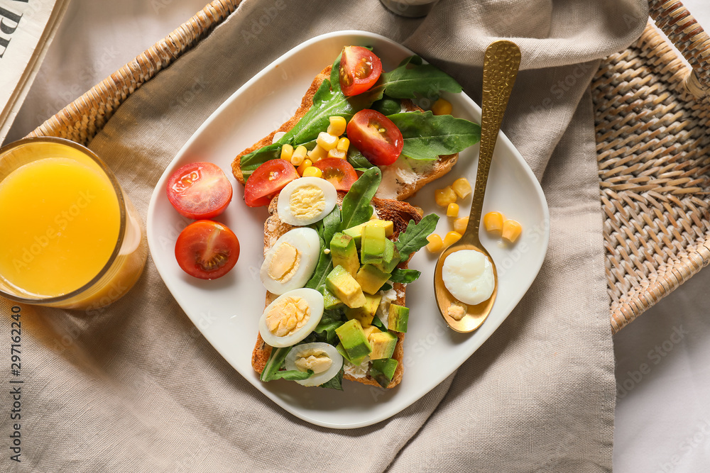 Tray with tasty sandwiches and juice on bed