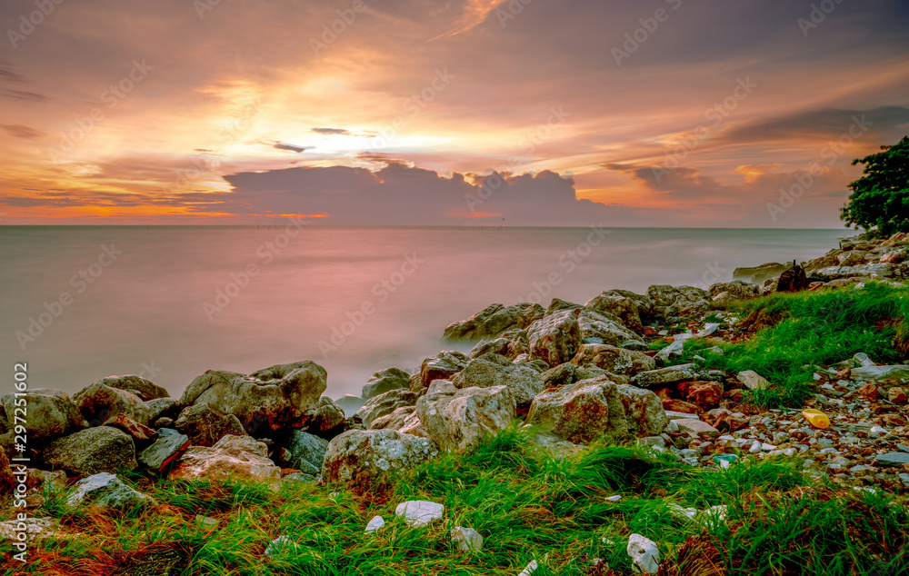 Rocks on stone beach at sunset. Beautiful beach sunset sky. Twilight sea and sky. Tropical sea at du