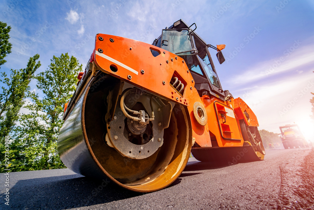 Road repair, compactor lays asphalt. Heavy special machines. Asphalt paver in operation. Side view. 