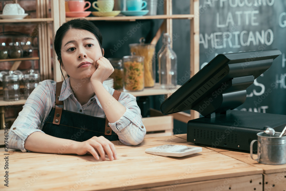 创业企业主的女人双手放在下巴上靠在酒吧柜台上等顾客。心烦意乱